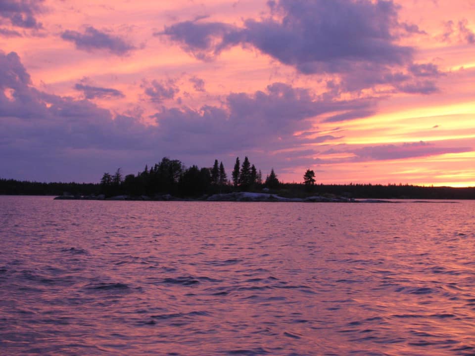 A sunset over a lake with a small island in the middle
