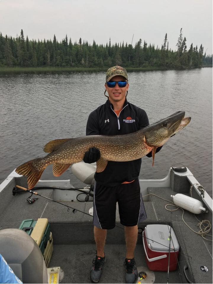 A man is standing on a boat holding a large fish