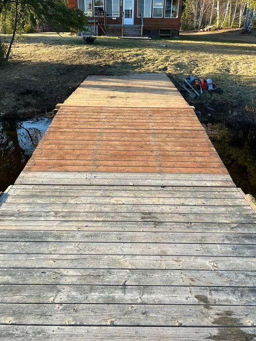 A wooden dock leading to a house in the background.