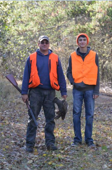 Two men in orange vests are standing next to each other