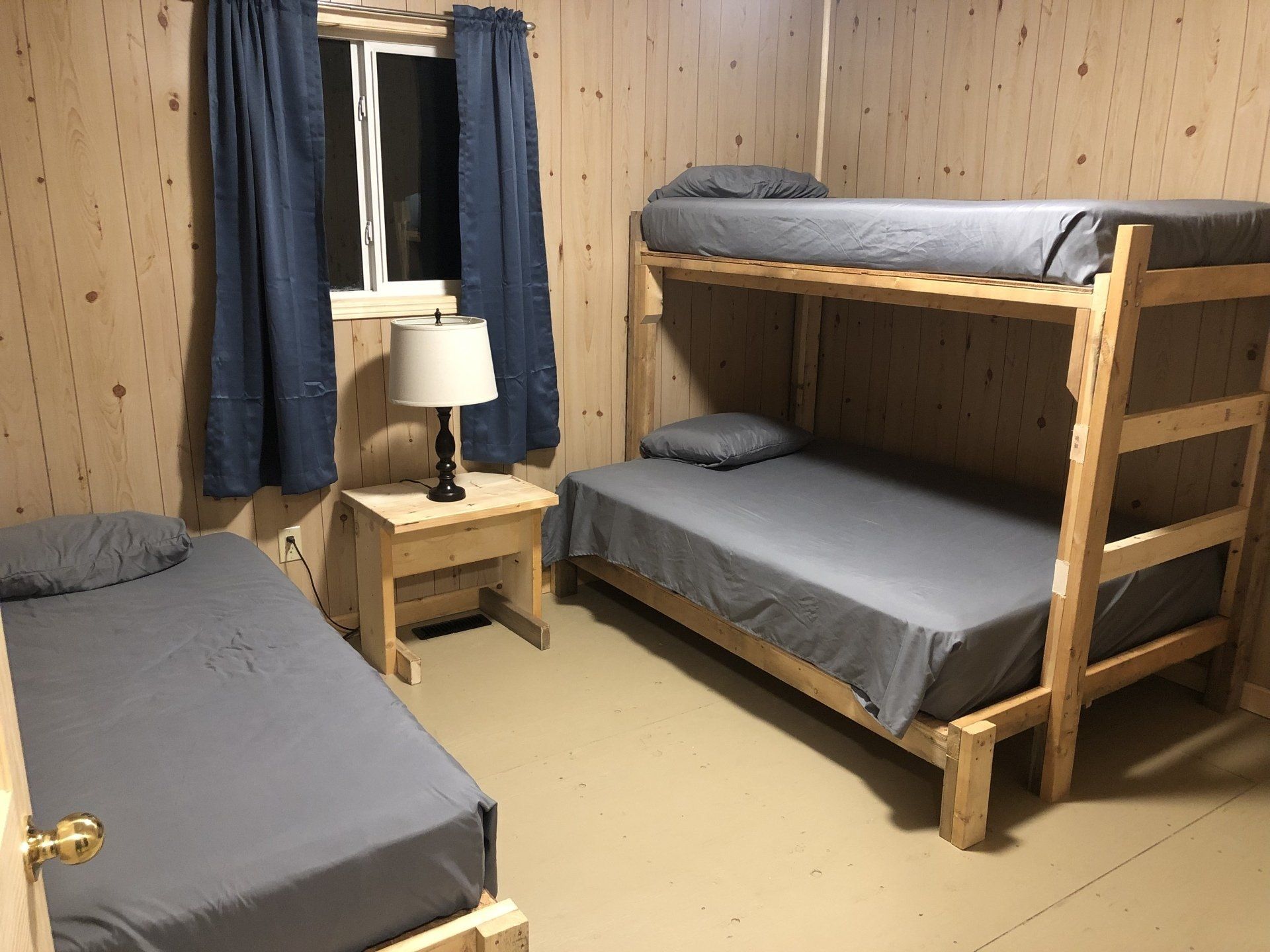 A bedroom with two bunk beds and a lamp.