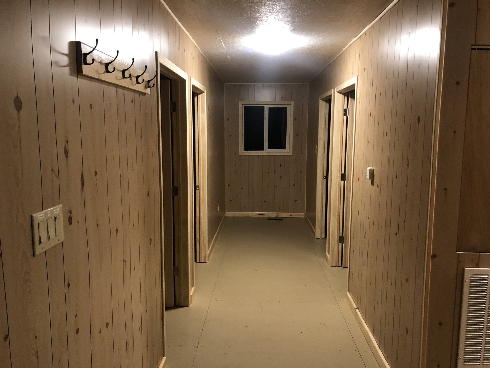 A long hallway with wood paneling and a window