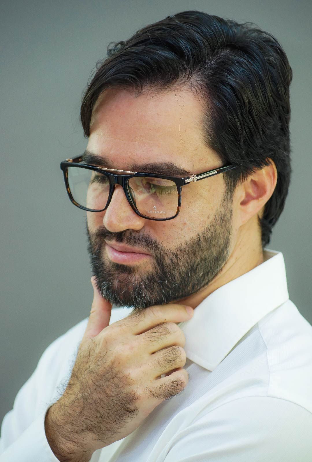 Un hombre con barba, lentes y camisa blanca.
