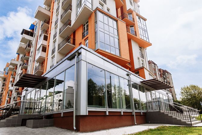 Moderno edificio residenziale a più piani con facciata arancione e ampliamento al piano terra interamente vetrato.