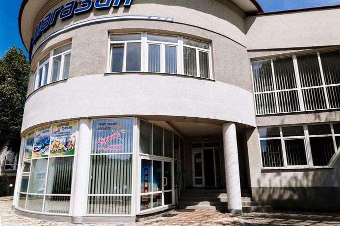 Un moderno edificio per uffici a due piani, dalla forma curva, con vetrine in vetro, intonaco chiaro e un ingresso.