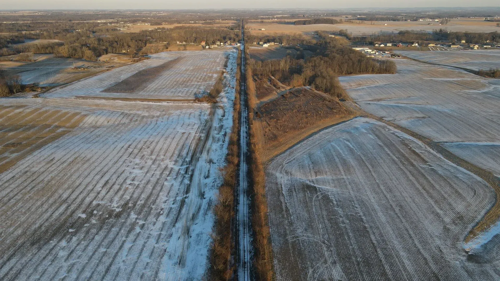 An aerial view of a train track going through a snowy field.