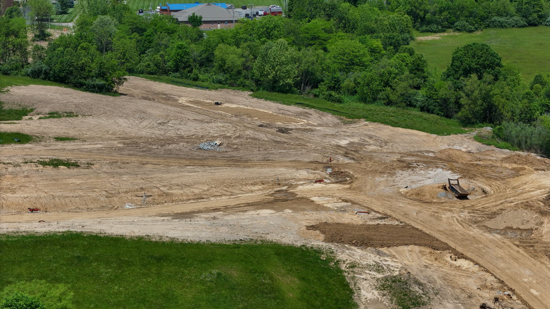 An aerial view of a dirt field with trees in the background.