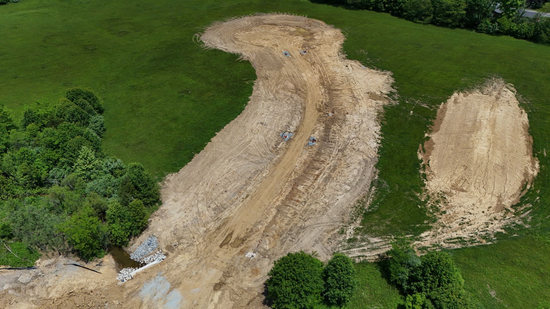 An aerial view of a dirt road going through a grassy field.