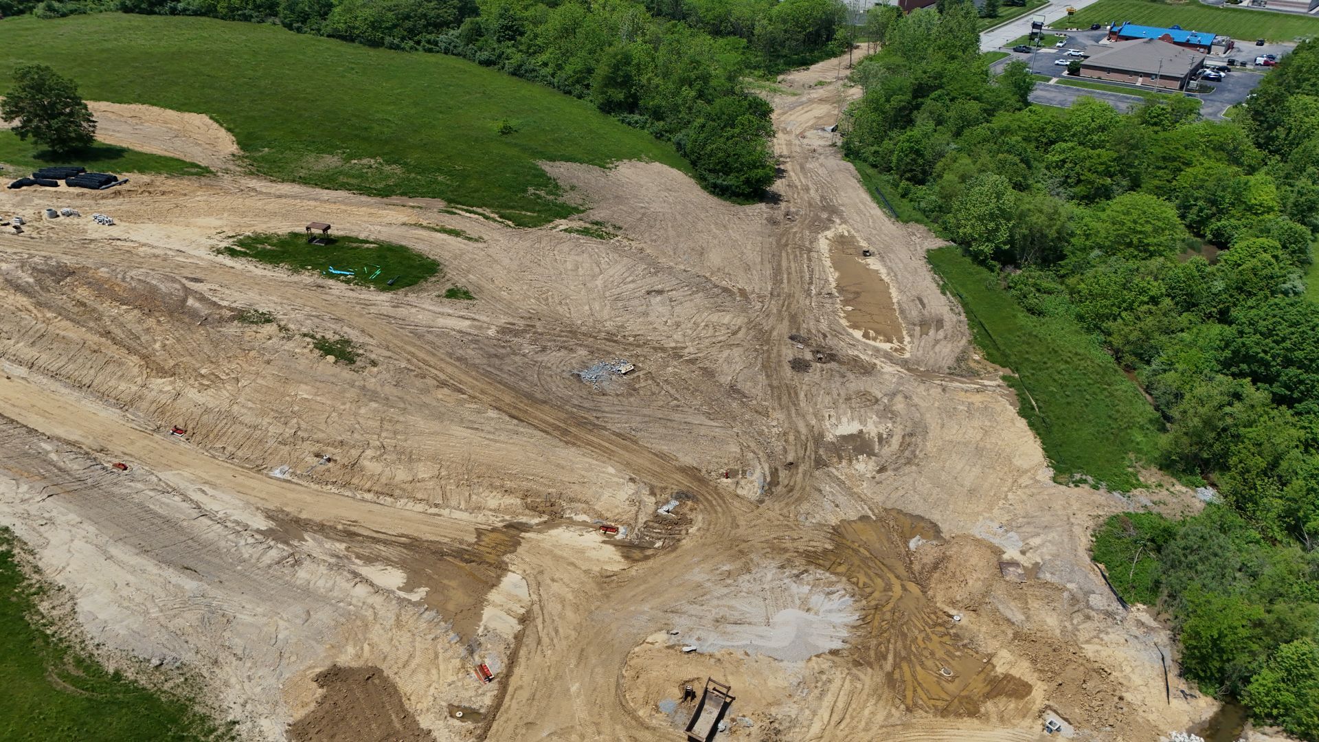 An aerial view of a construction site surrounded by trees and dirt.