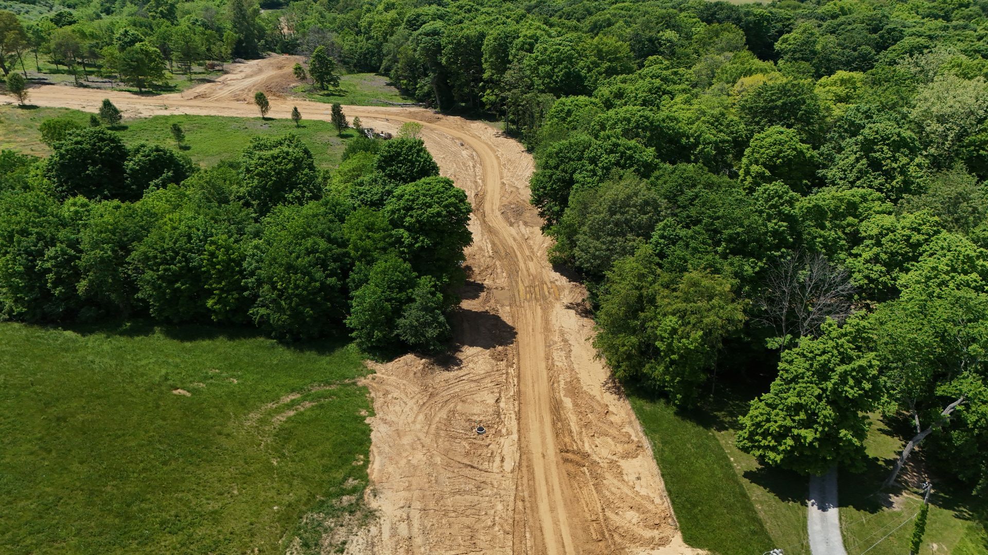 An aerial view of a dirt road surrounded by trees and grass.