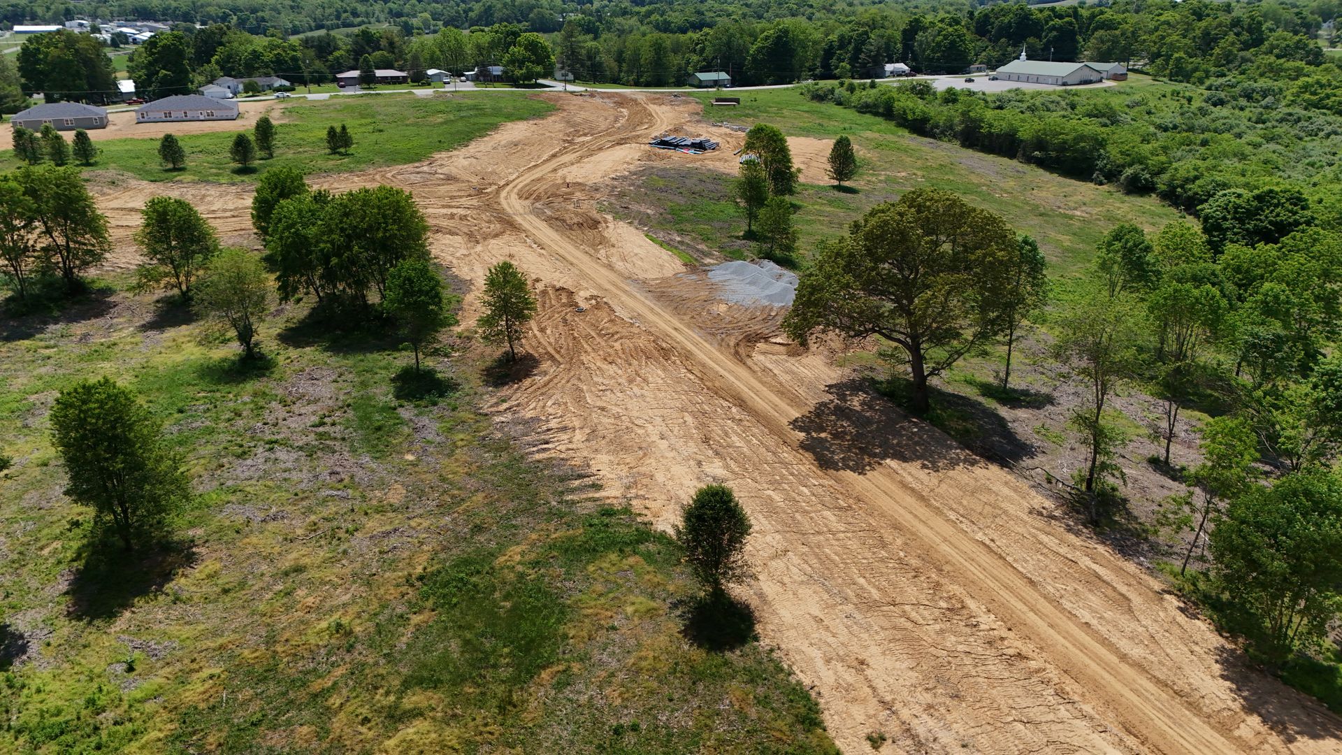 An aerial view of a dirt road surrounded by trees and grass.