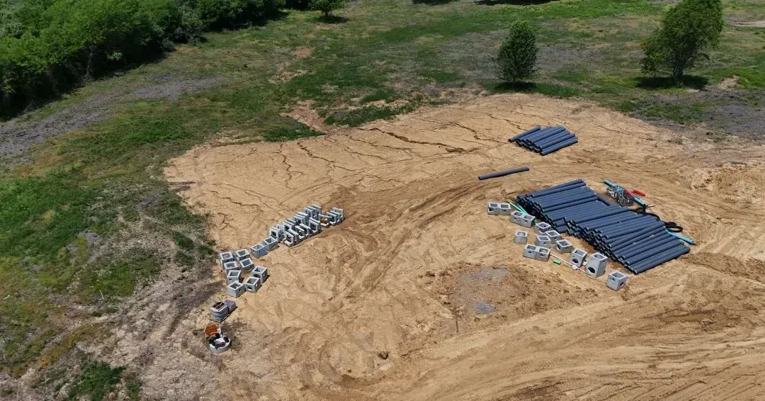 An aerial view of a construction site with a lot of dirt and trees.