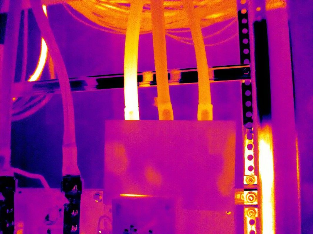 A purple and orange image of electrical wires in a server rack.