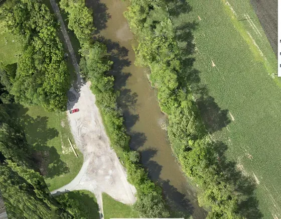 An aerial view of a river surrounded by trees and grass.