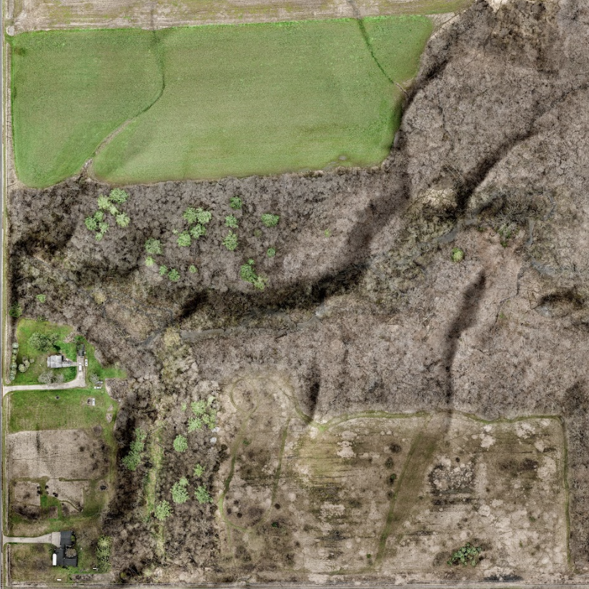 An aerial view of a field with a house in the middle