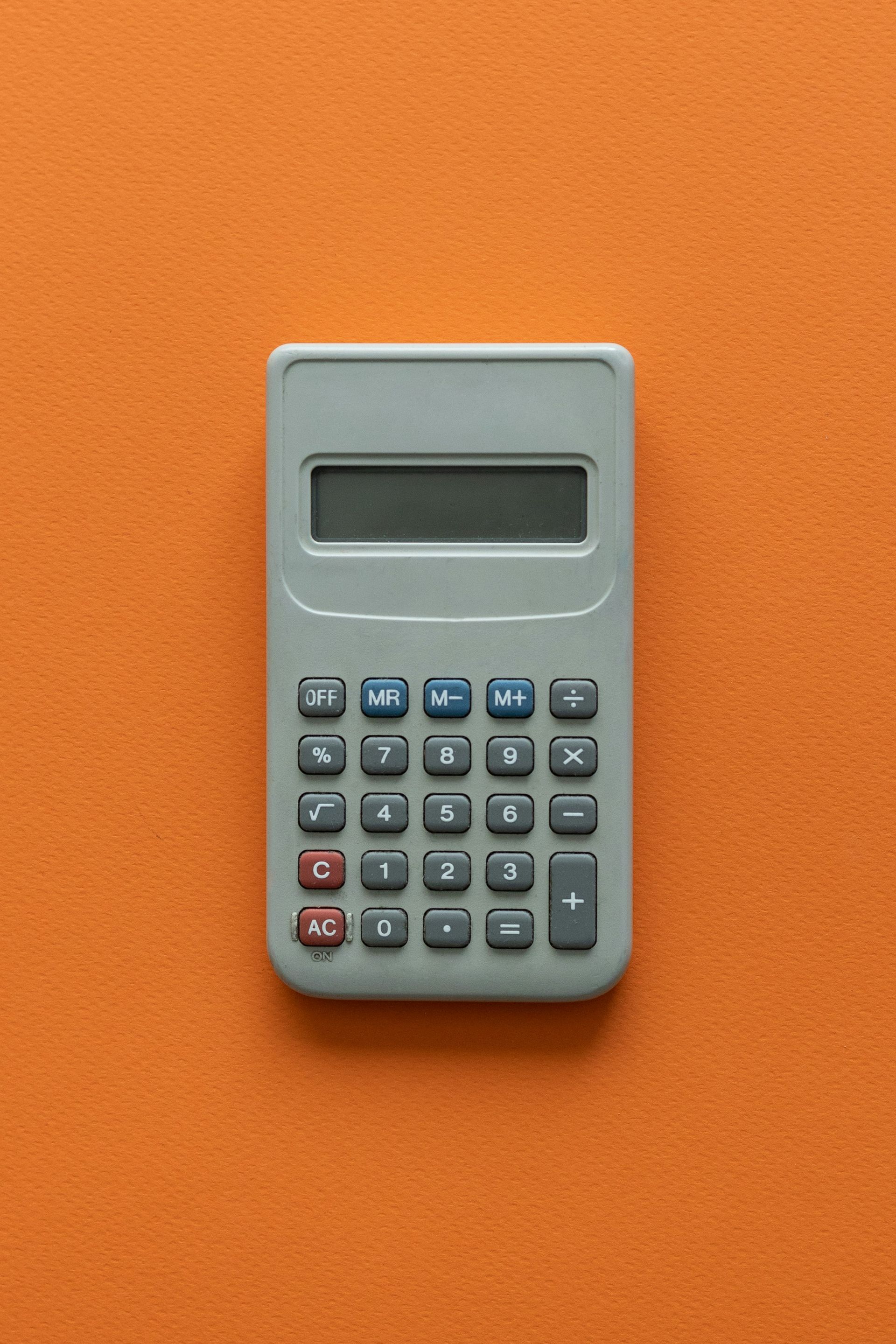 A calculator is sitting on top of an orange surface.
