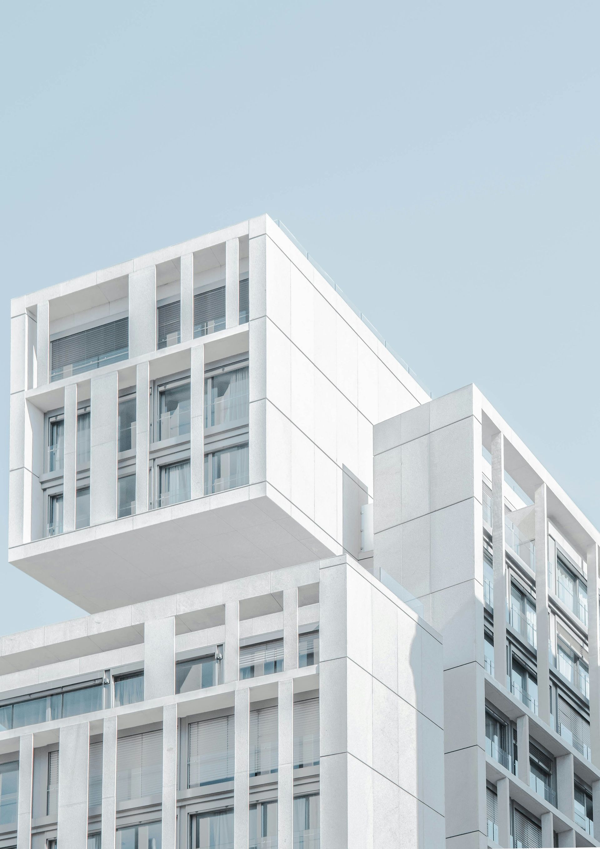 Modern white building with cantilevered section against a light blue sky.