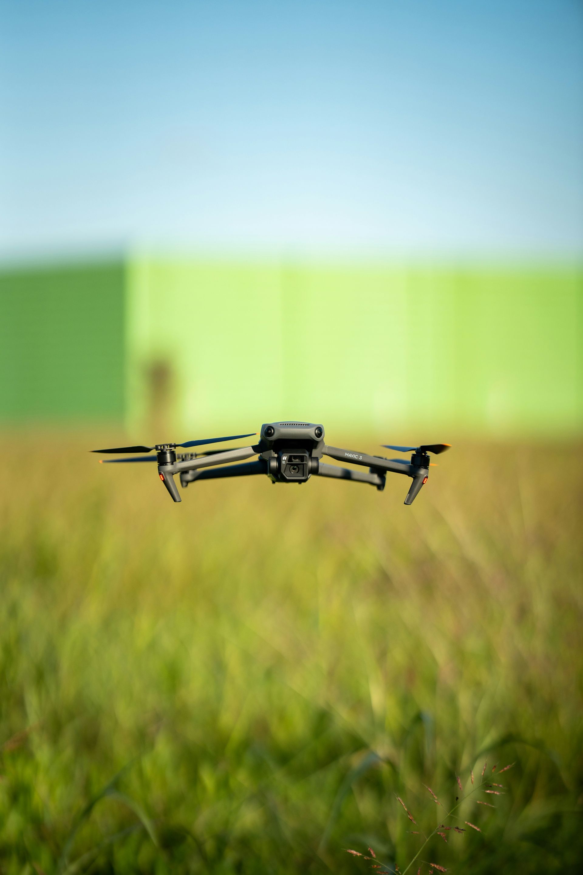Drone hovering over a field of grass with green background.