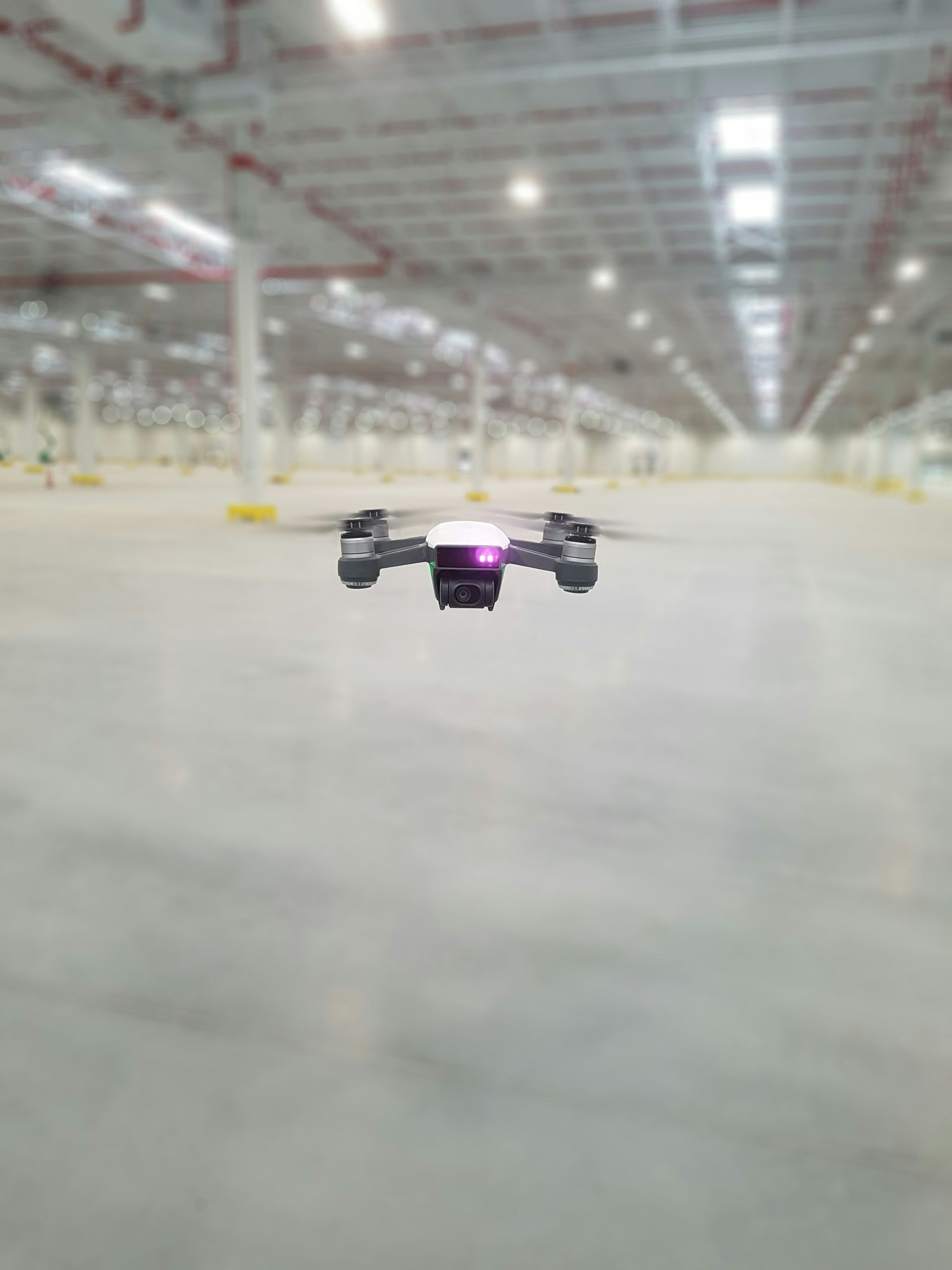 Drone hovering in a large, empty warehouse.