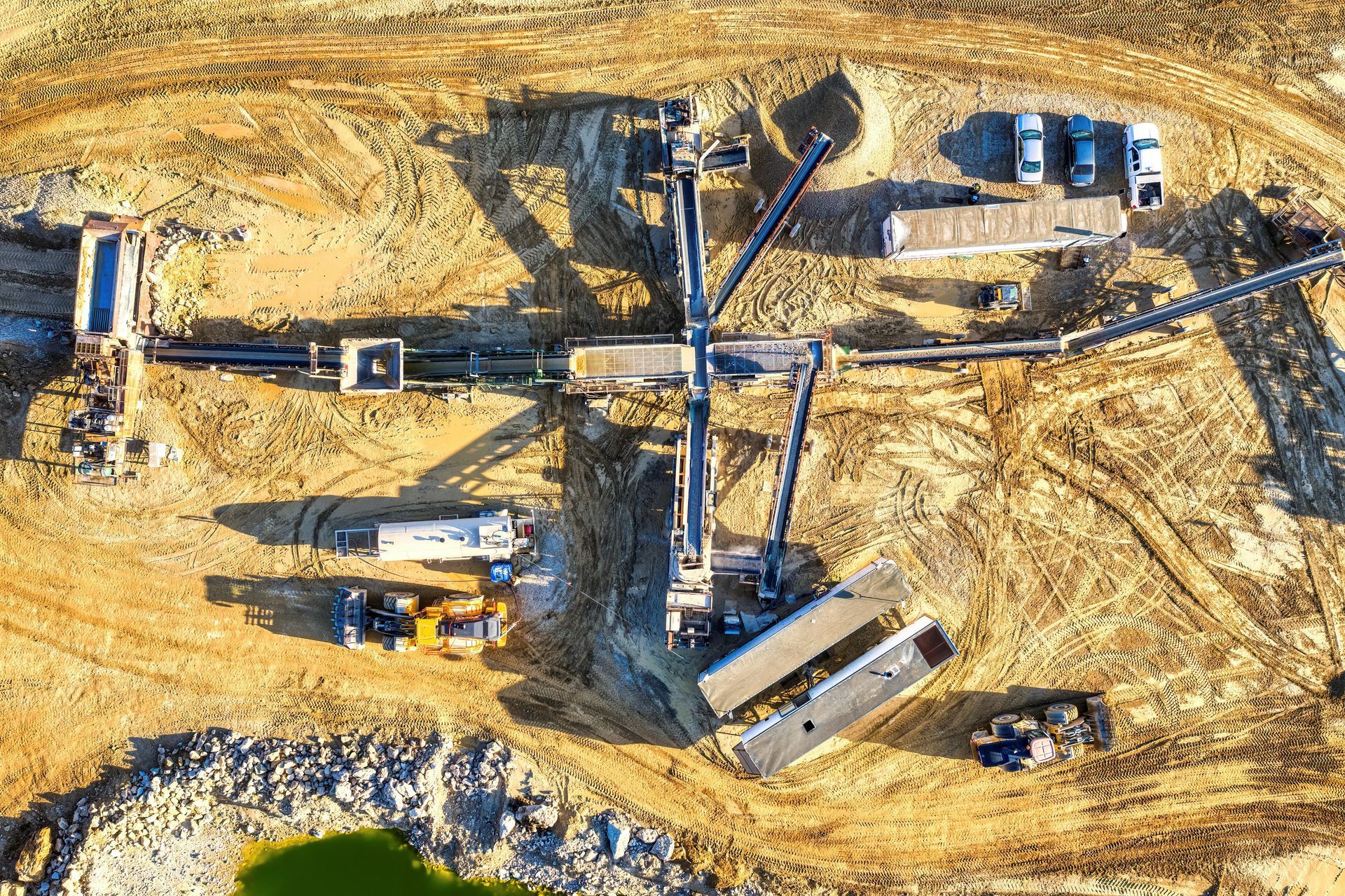 Aerial view of a mining operation with heavy machinery on a brown, dusty landscape.
