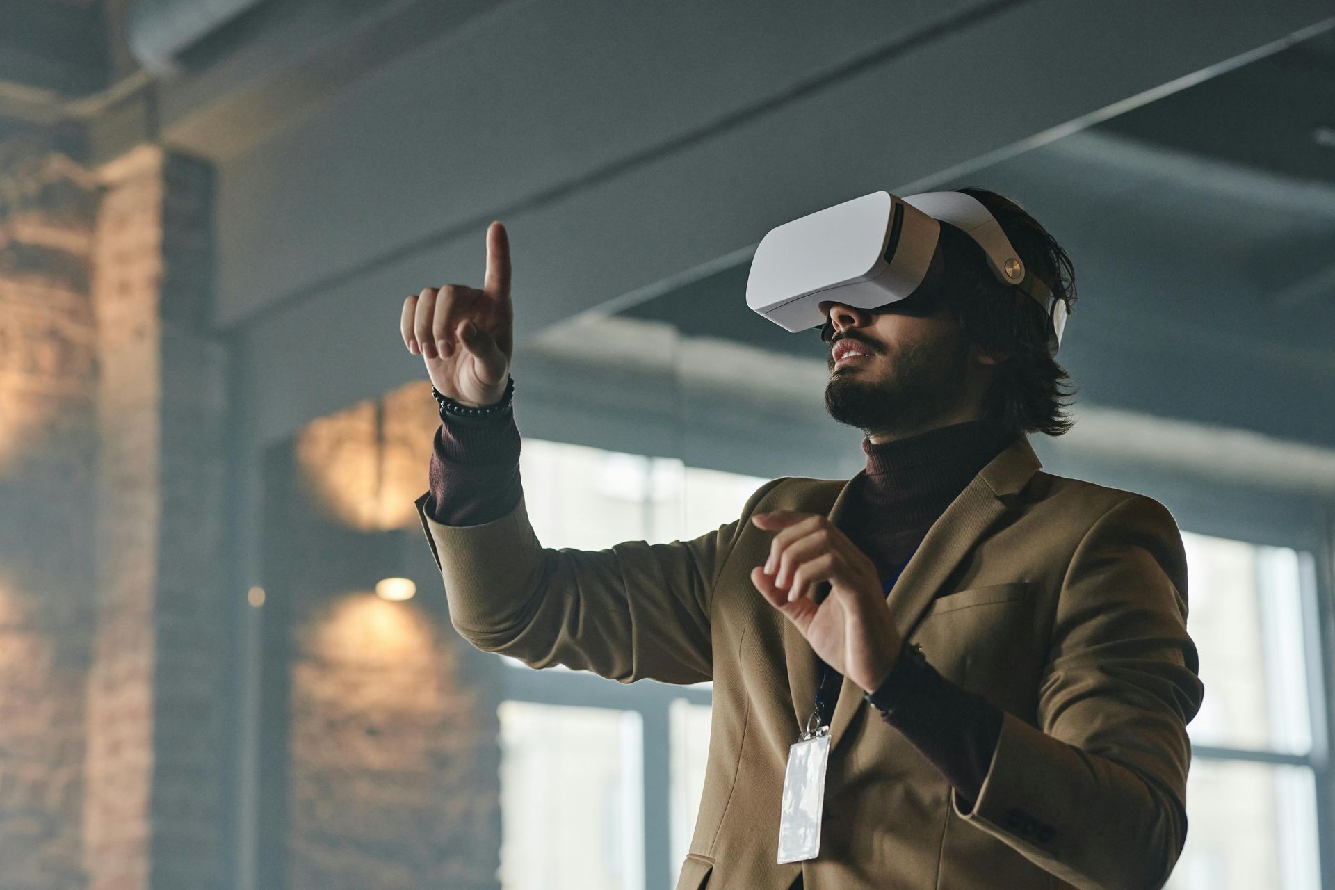 Man wearing VR headset, pointing up, in a modern office setting.