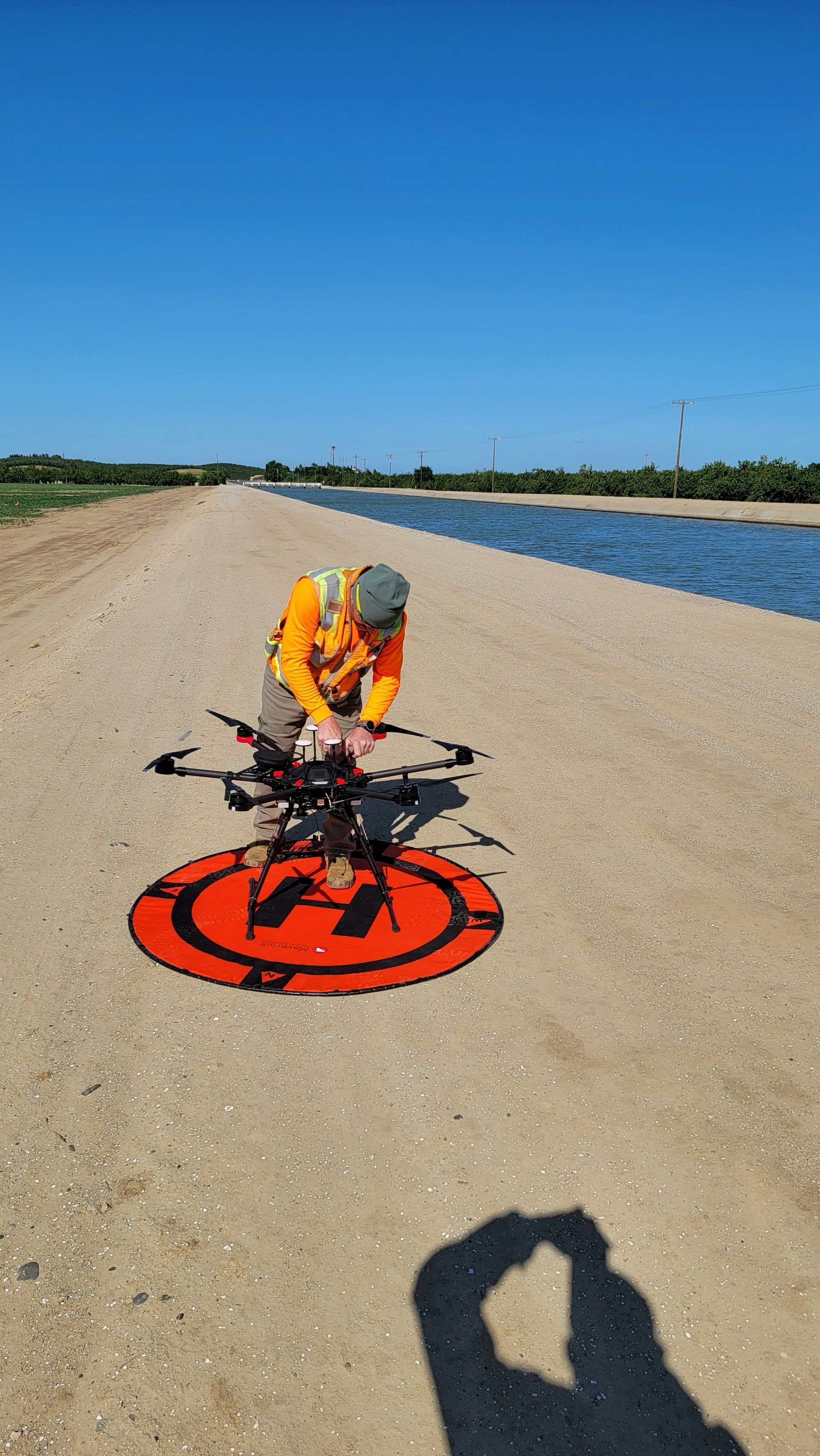A man is standing on a sandy beach holding a drone.