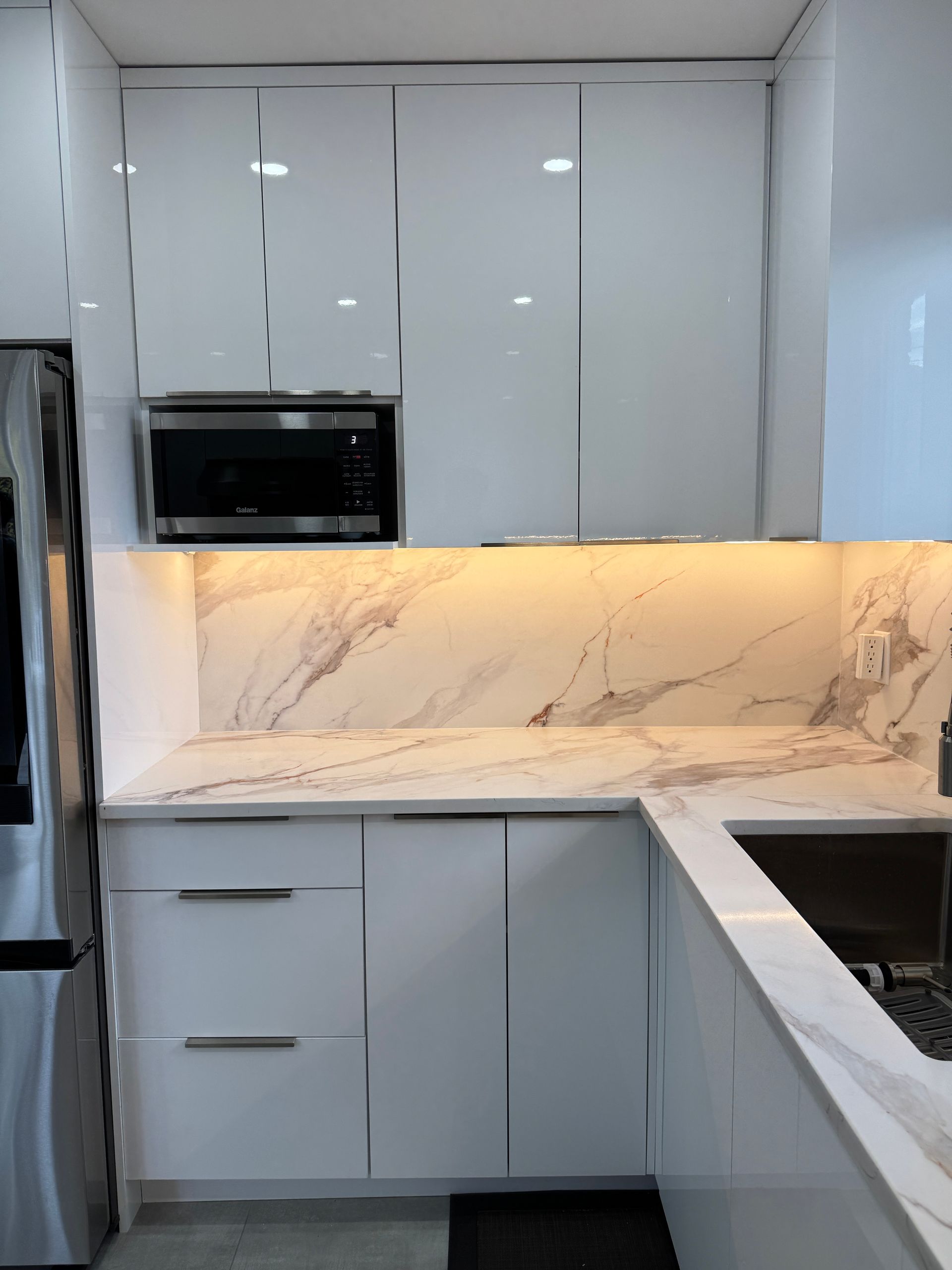 Une cuisine avec des armoires blanches et des comptoirs en marbre