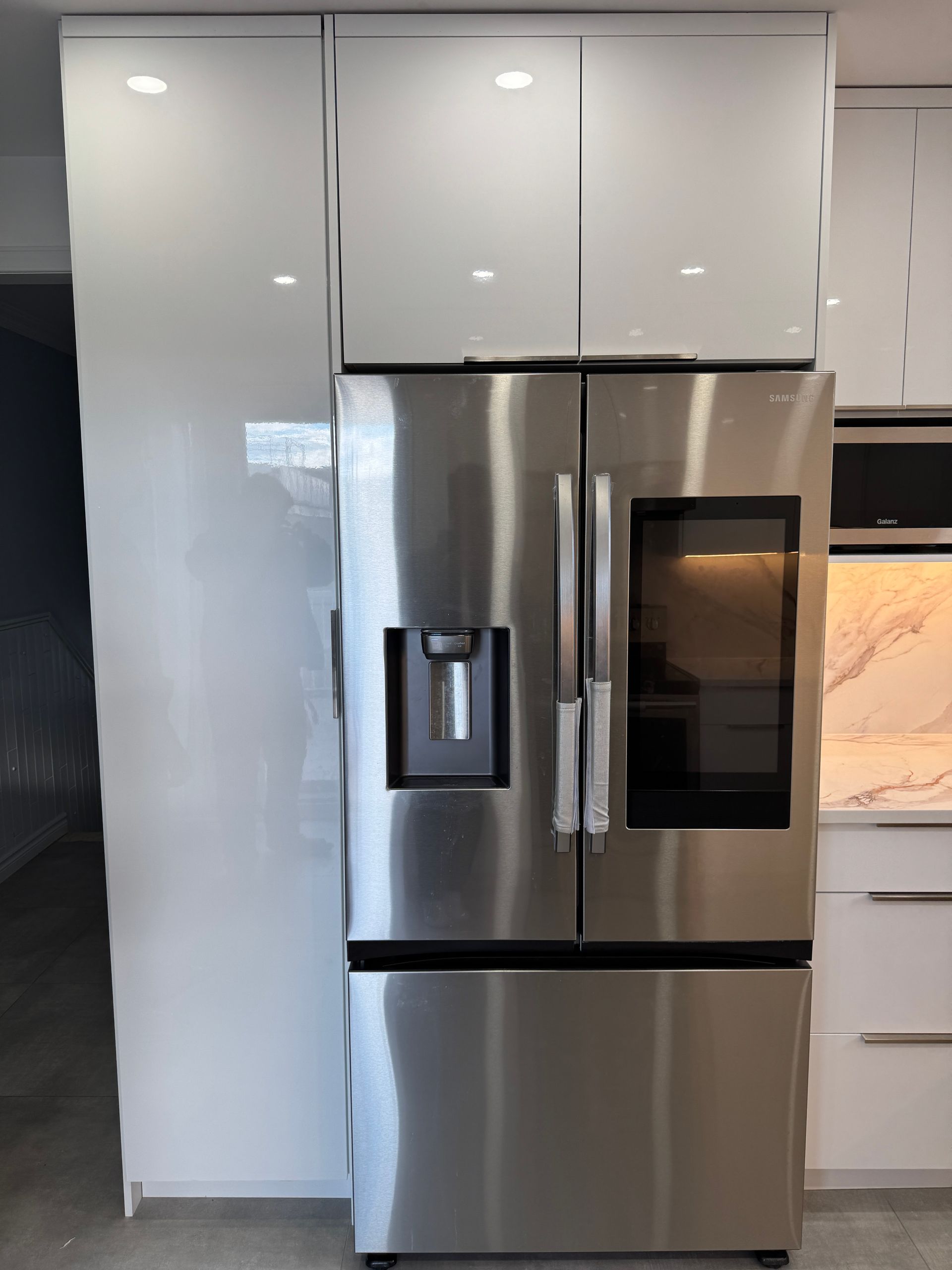 Un réfrigérateur en acier inoxydable dans une cuisine avec des armoires blanches