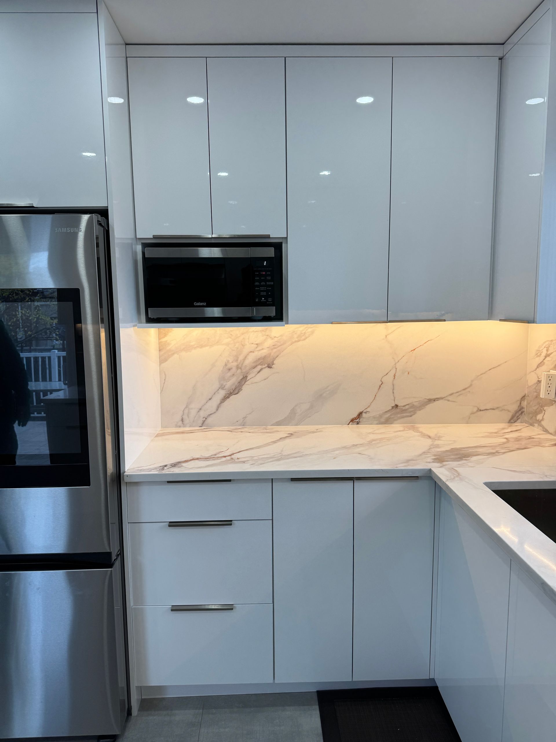 Une cuisine avec des armoires blanches et des appareils en acier inoxydable