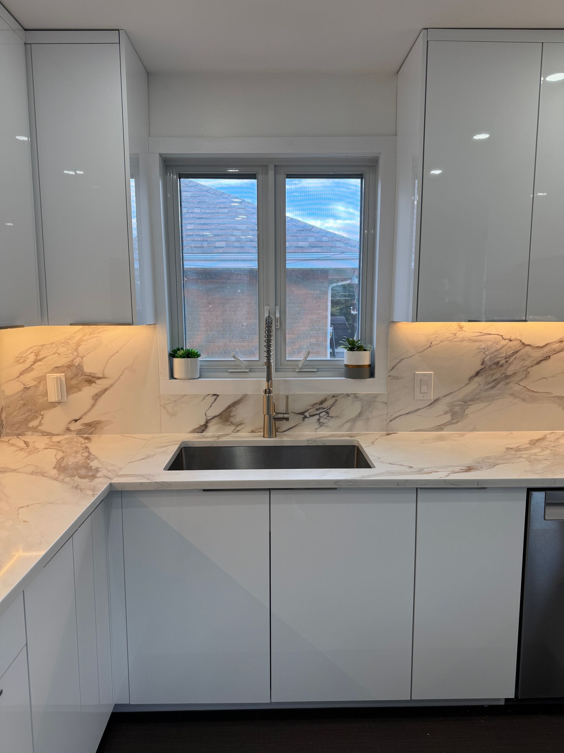 Une cuisine avec des armoires blanches et des comptoirs en marbre