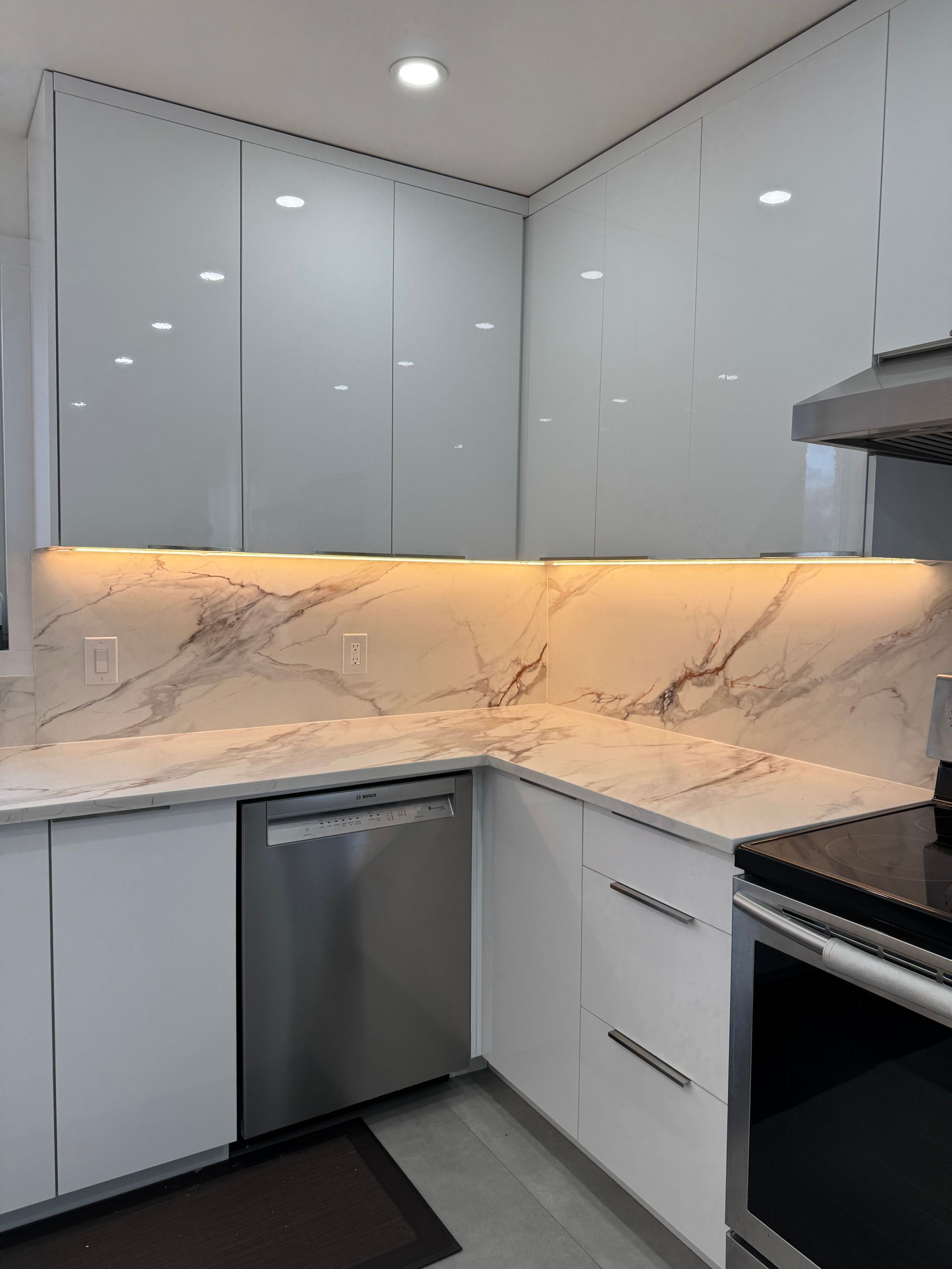 Une cuisine avec des armoires blanches, des appareils en acier inoxydable et des comptoirs en marbre.