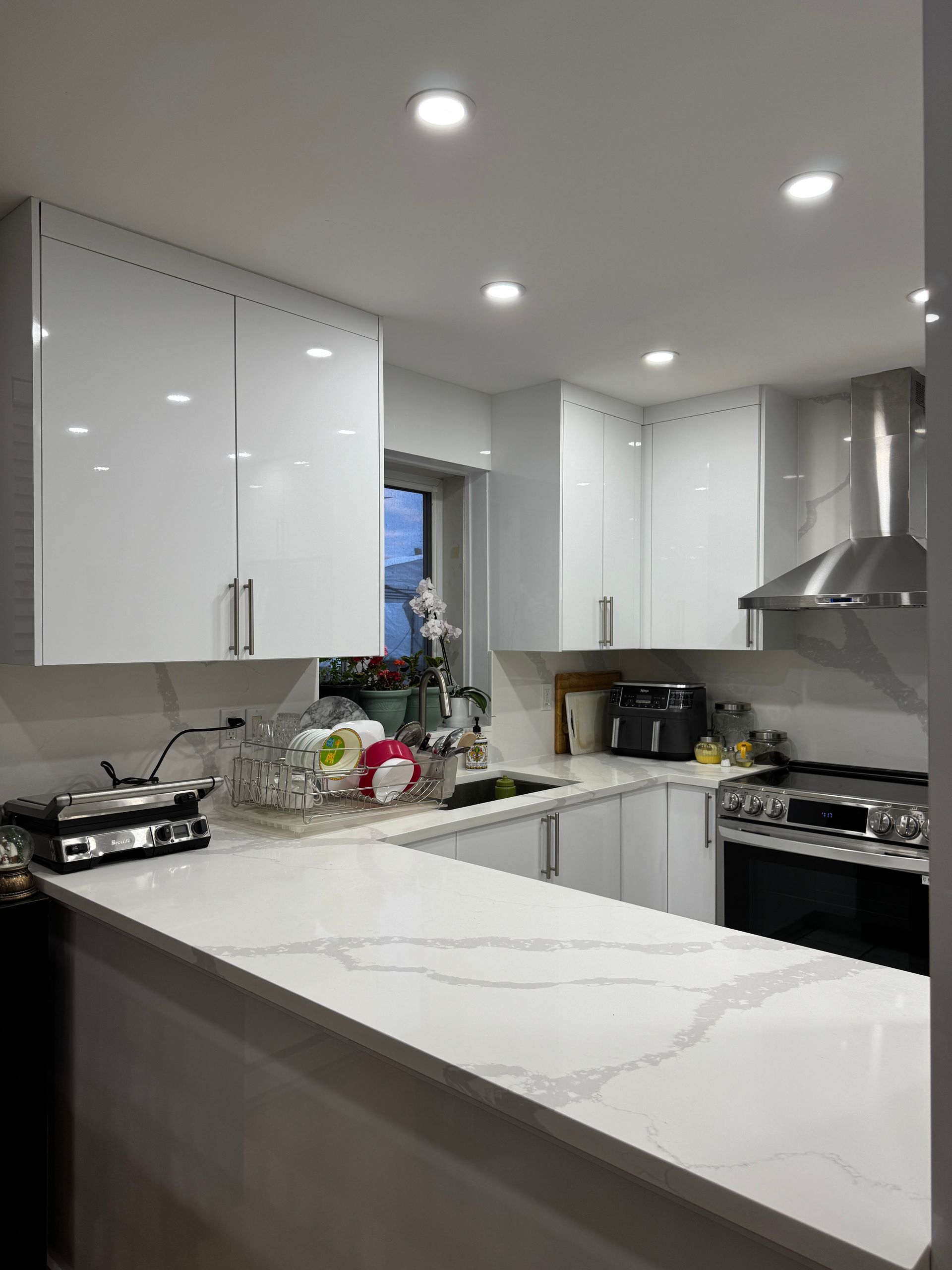 Une cuisine avec des armoires blanches, une cuisinière, un évier et un comptoir.