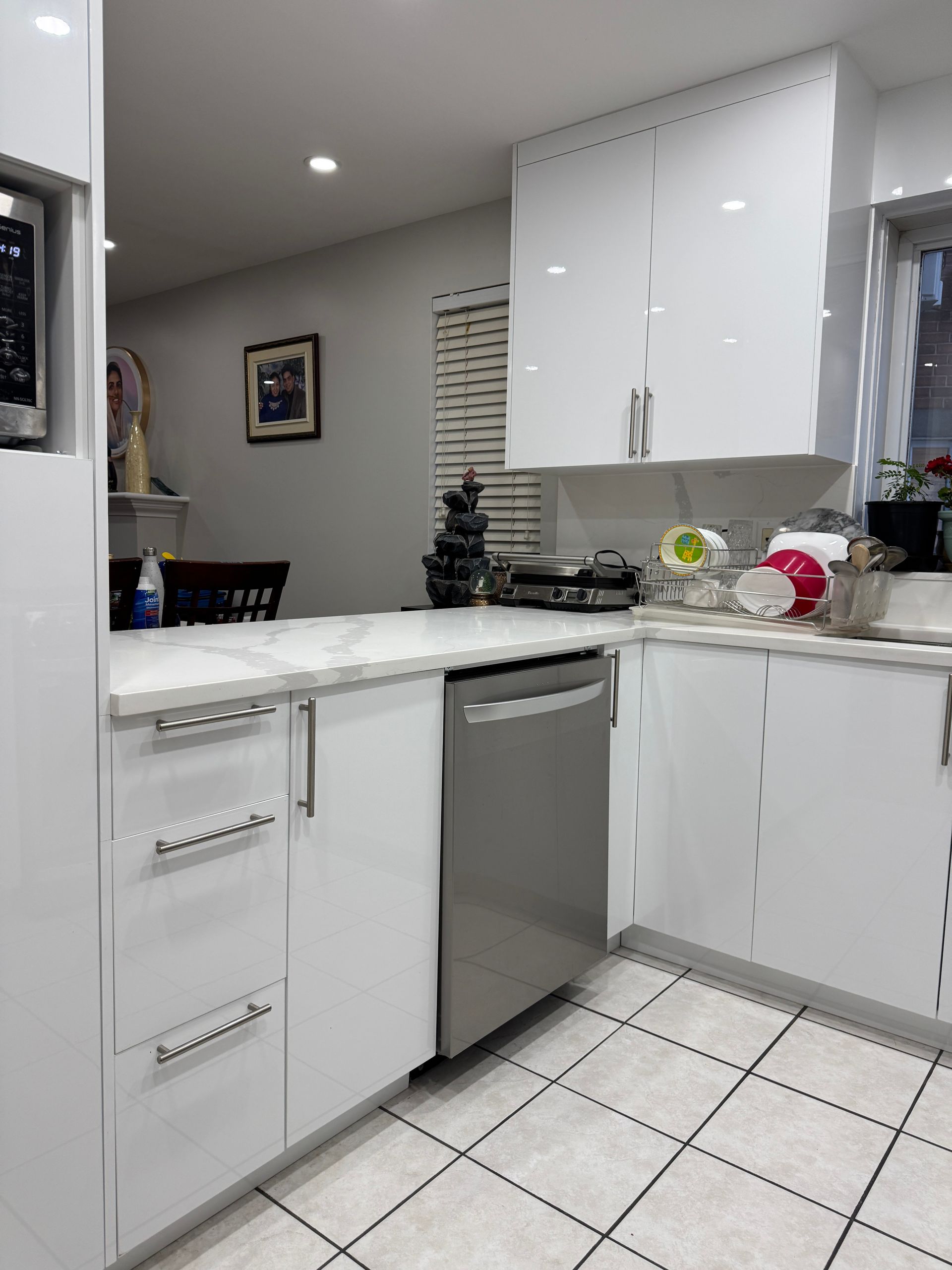 Une cuisine avec des armoires blanches et un lave-vaisselle en acier inoxydable.