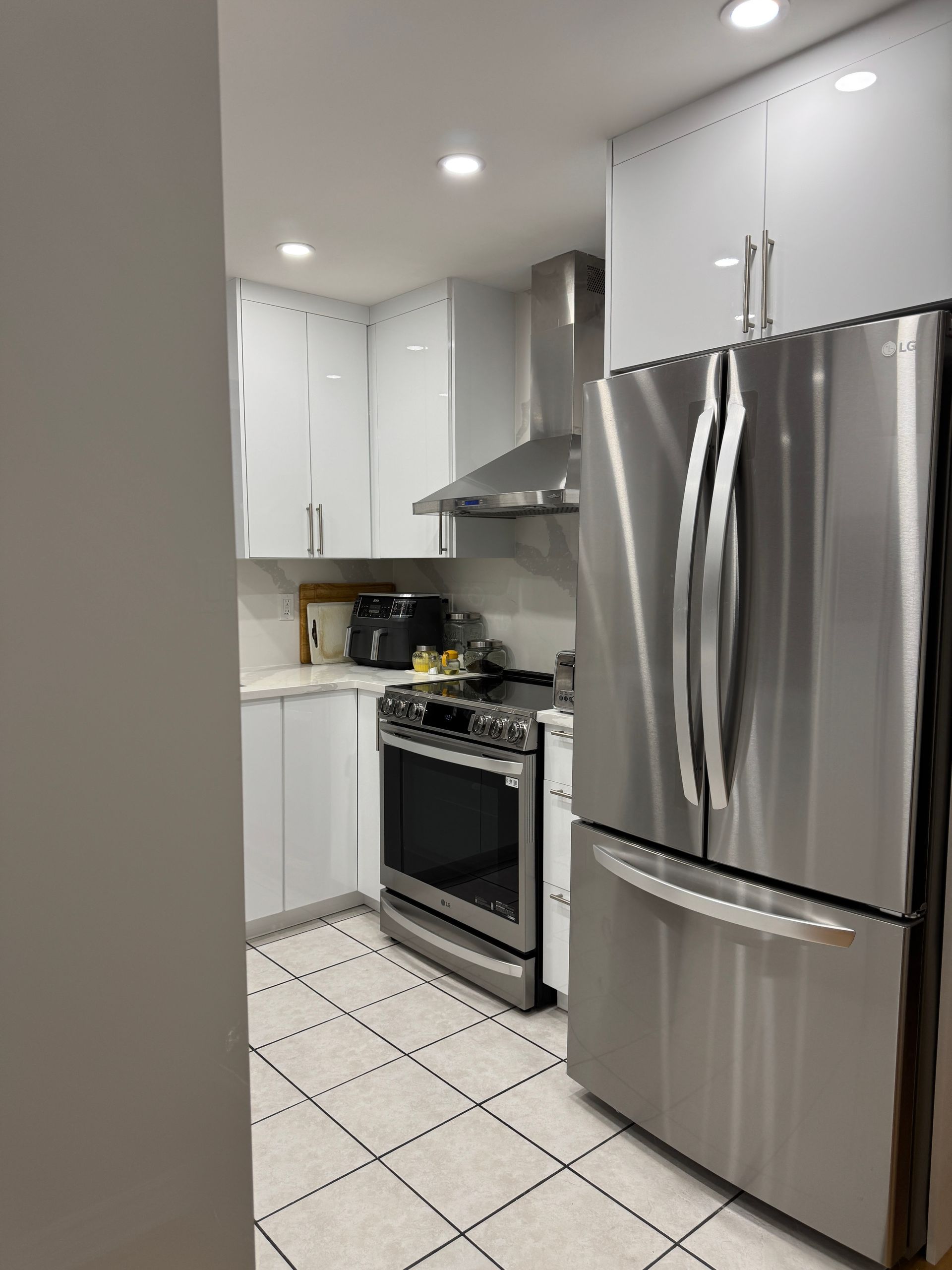 Une cuisine avec des appareils électroménagers en acier inoxydable et des armoires blanches.