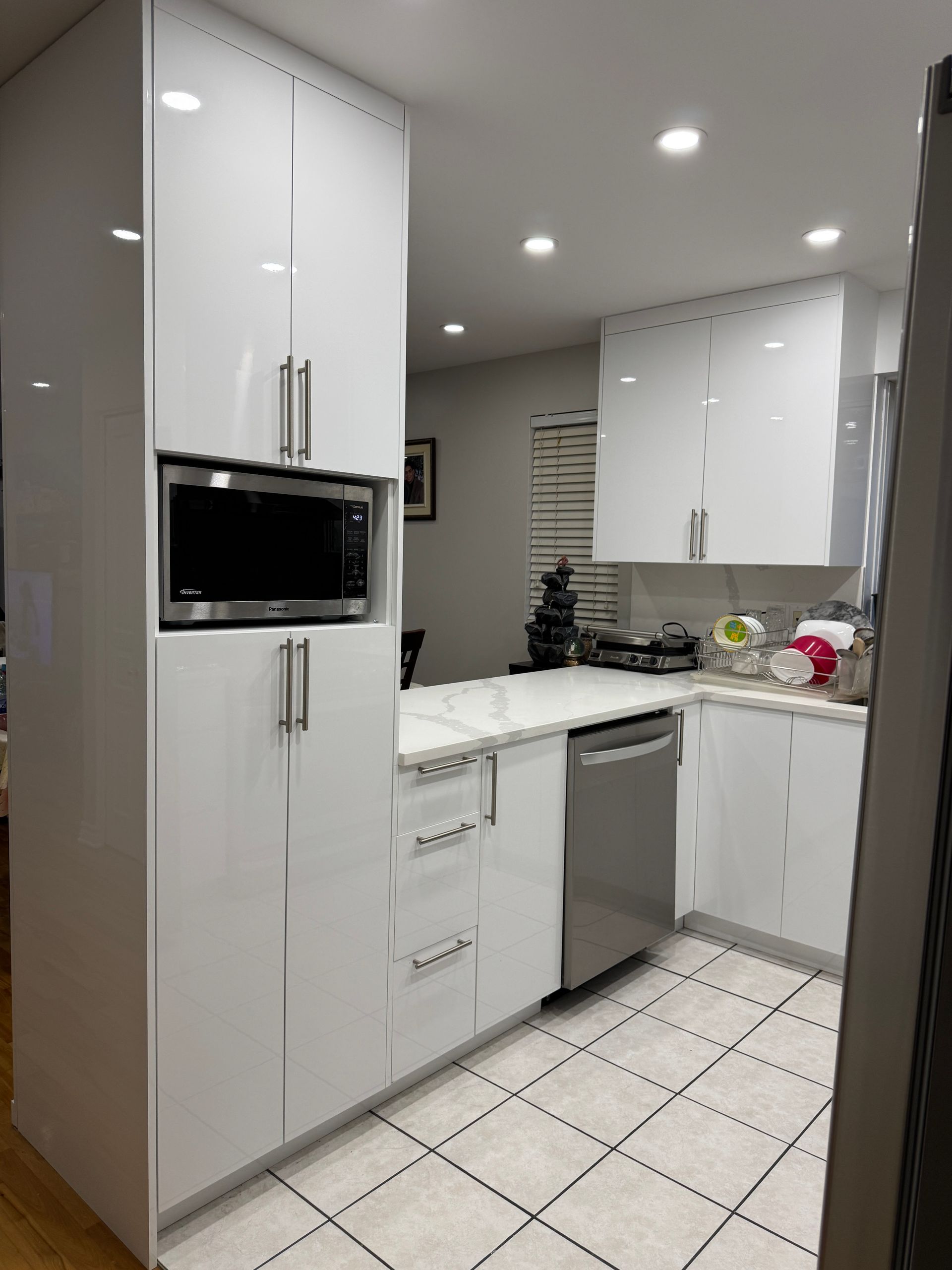 Une cuisine avec des armoires blanches et un lave-vaisselle en acier inoxydable.