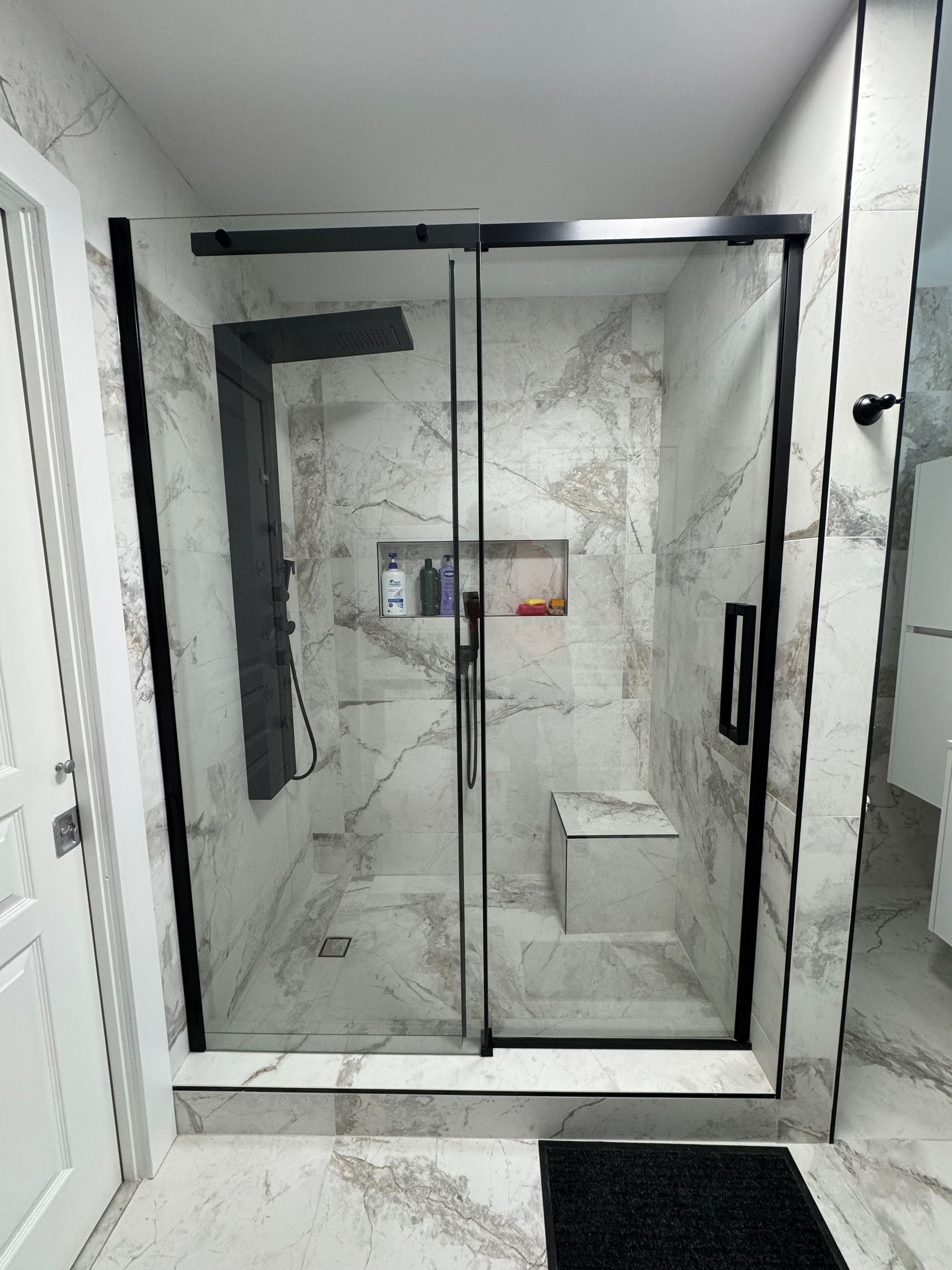 Une salle de bain avec douche à l'italienne avec portes coulissantes en verre.