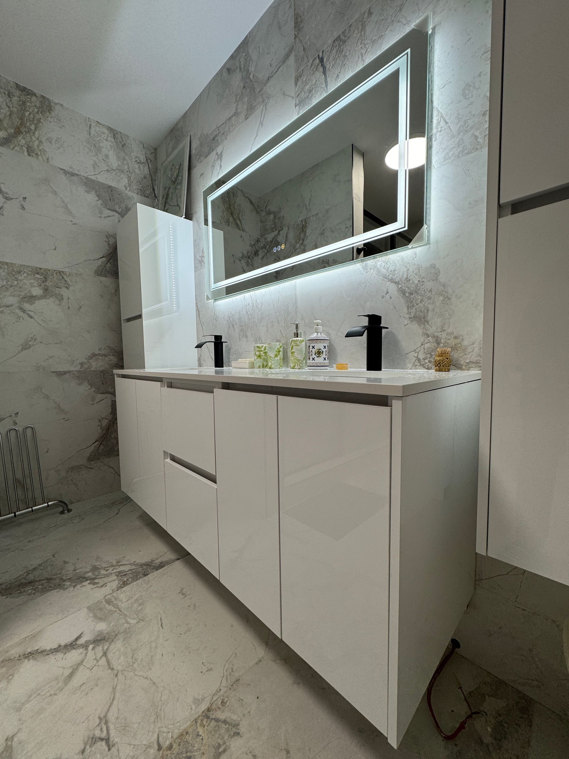 Une salle de bain avec deux lavabos et un miroir au mur.