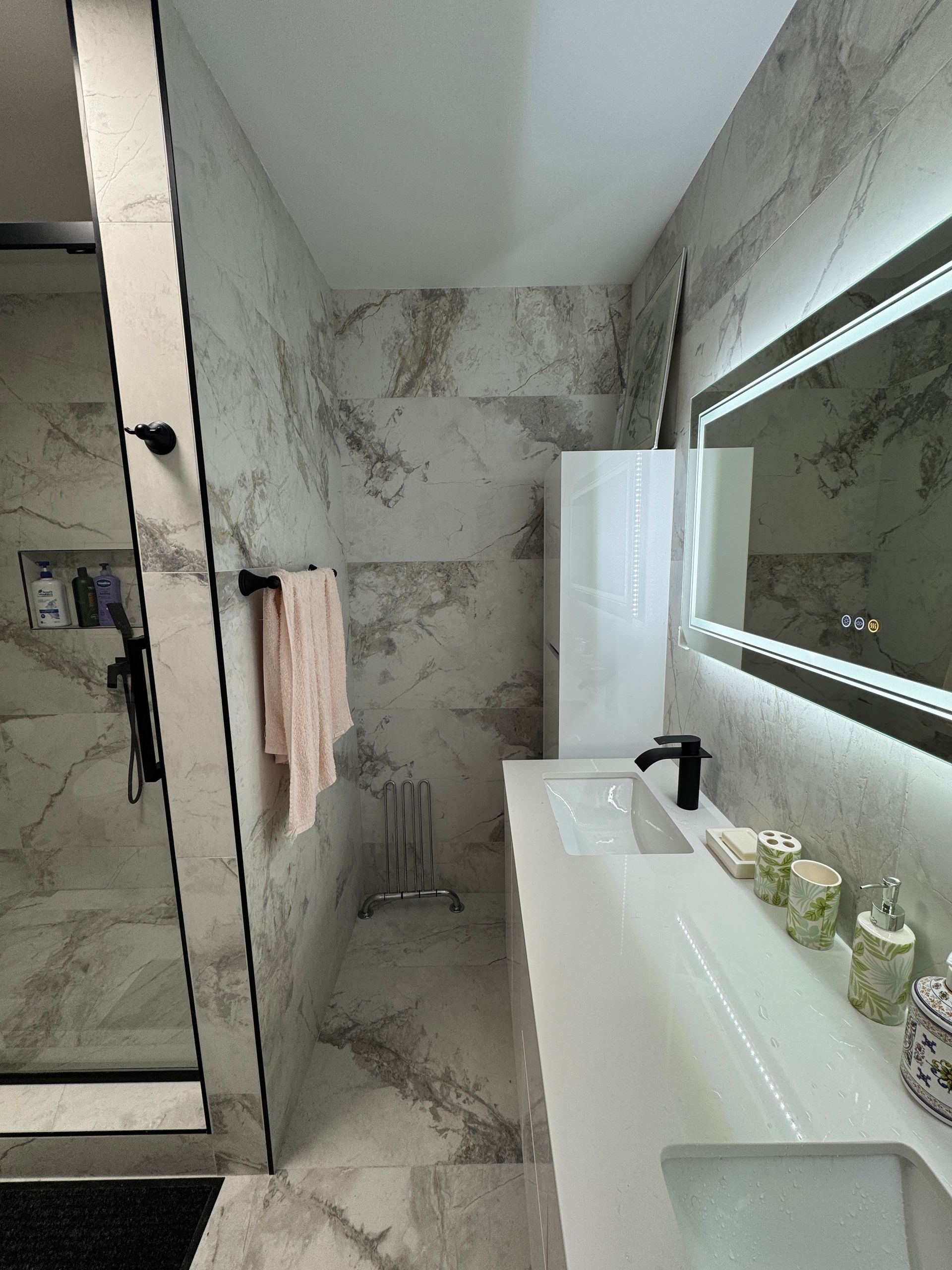 Une salle de bain avec lavabo, miroir et douche.