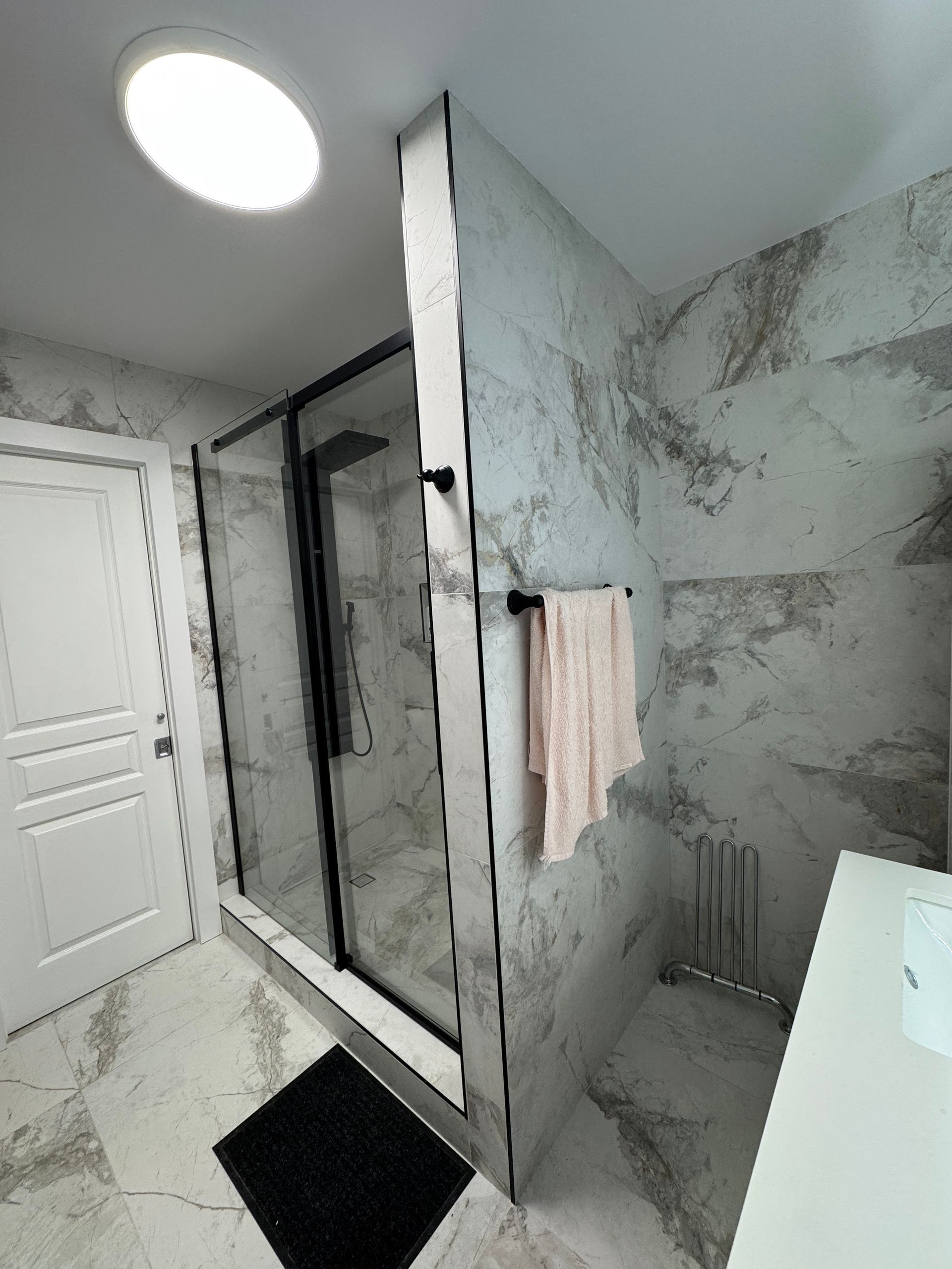 Une salle de bain avec douche à l'italienne et puits de lumière.