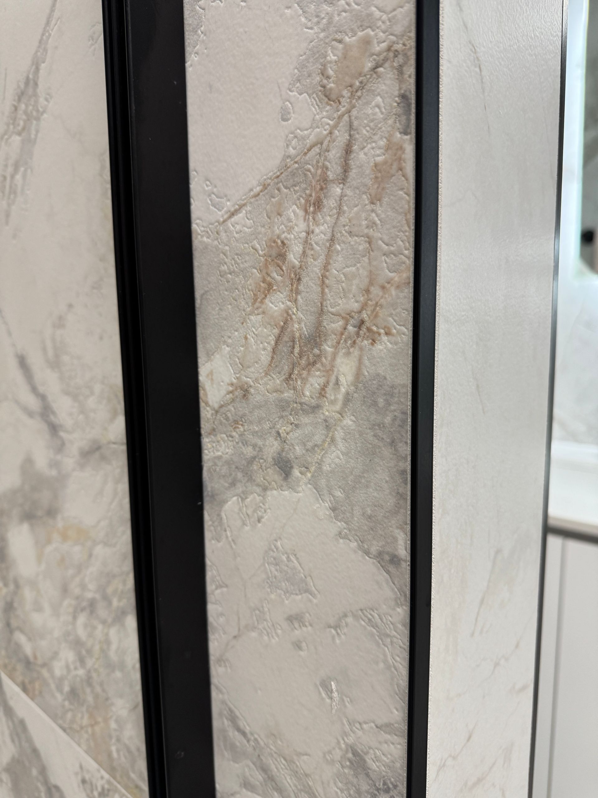 Un gros plan d'un mur en marbre avec un cadre noir.