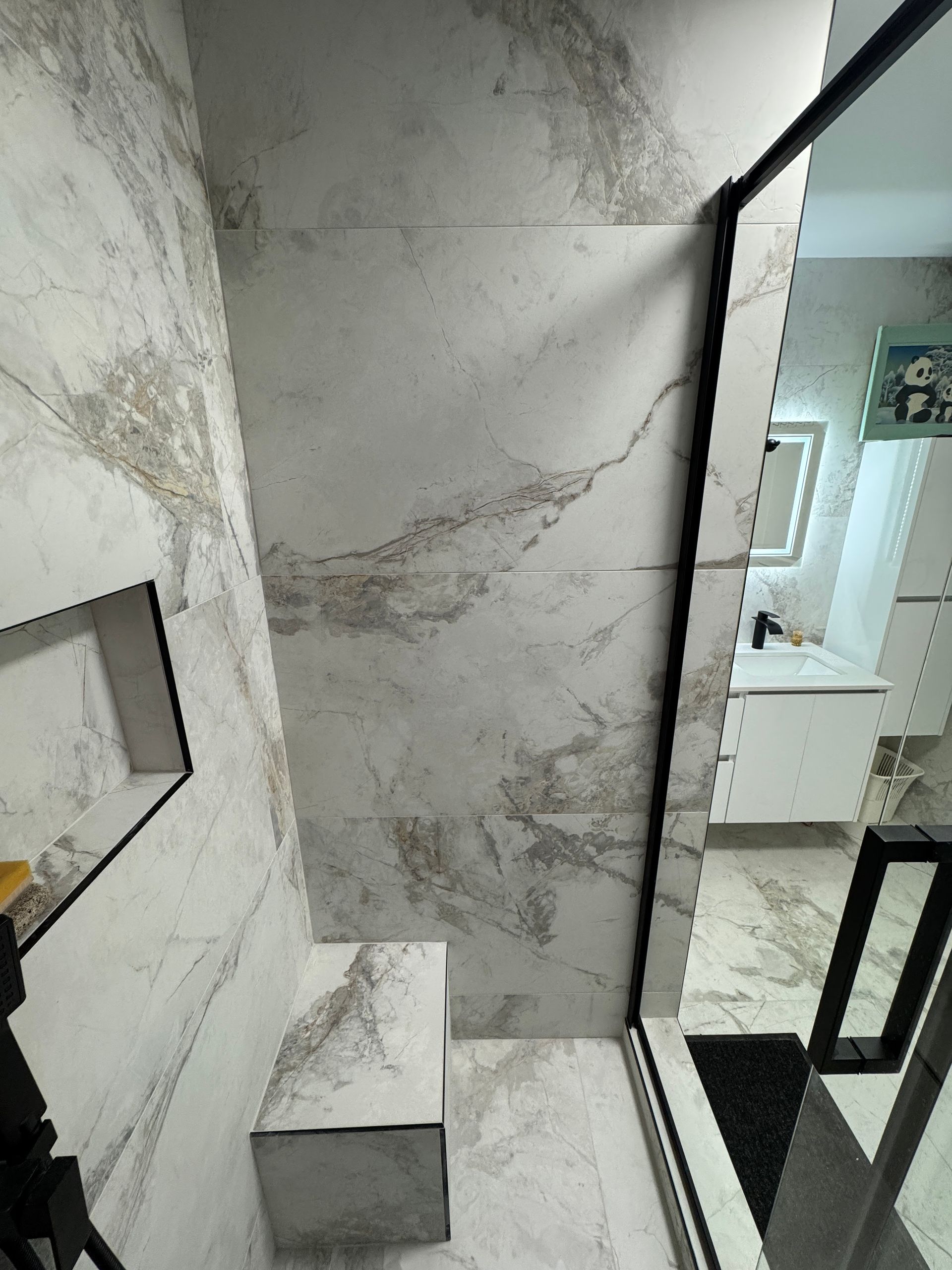 Une salle de bain avec carrelage en marbre et douche à l'italienne.