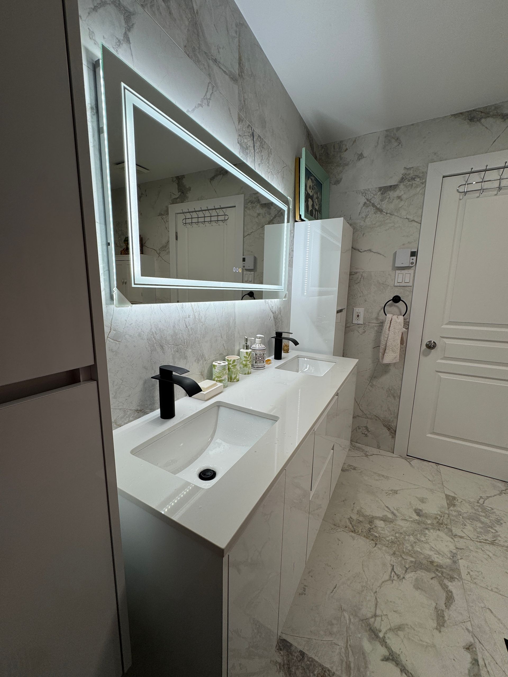 Une salle de bain avec deux lavabos et un grand miroir.