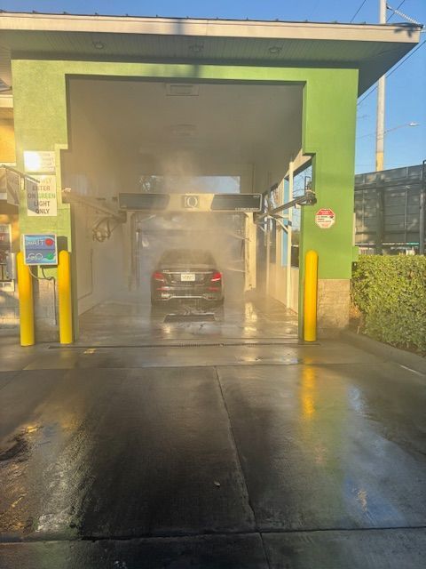 White car being washed at a car wash; water spraying on the car.