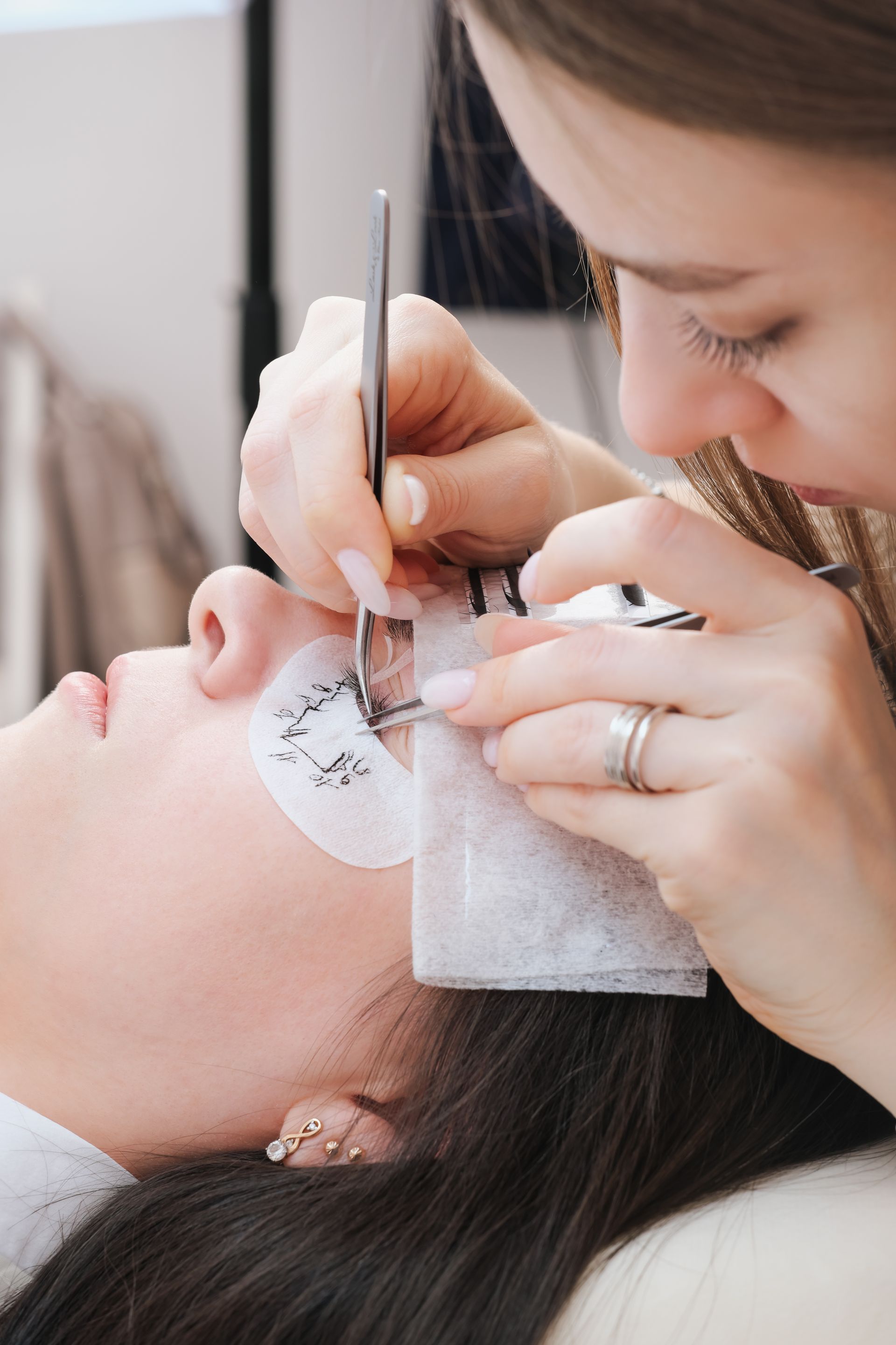 A woman is getting her eyelashes done by a makeup artist.