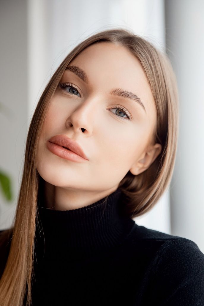 A woman with long hair is wearing a black turtleneck and looking at the camera.