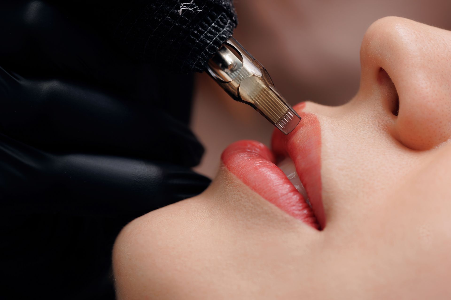 A woman is getting a permanent makeup tattoo on her lips.