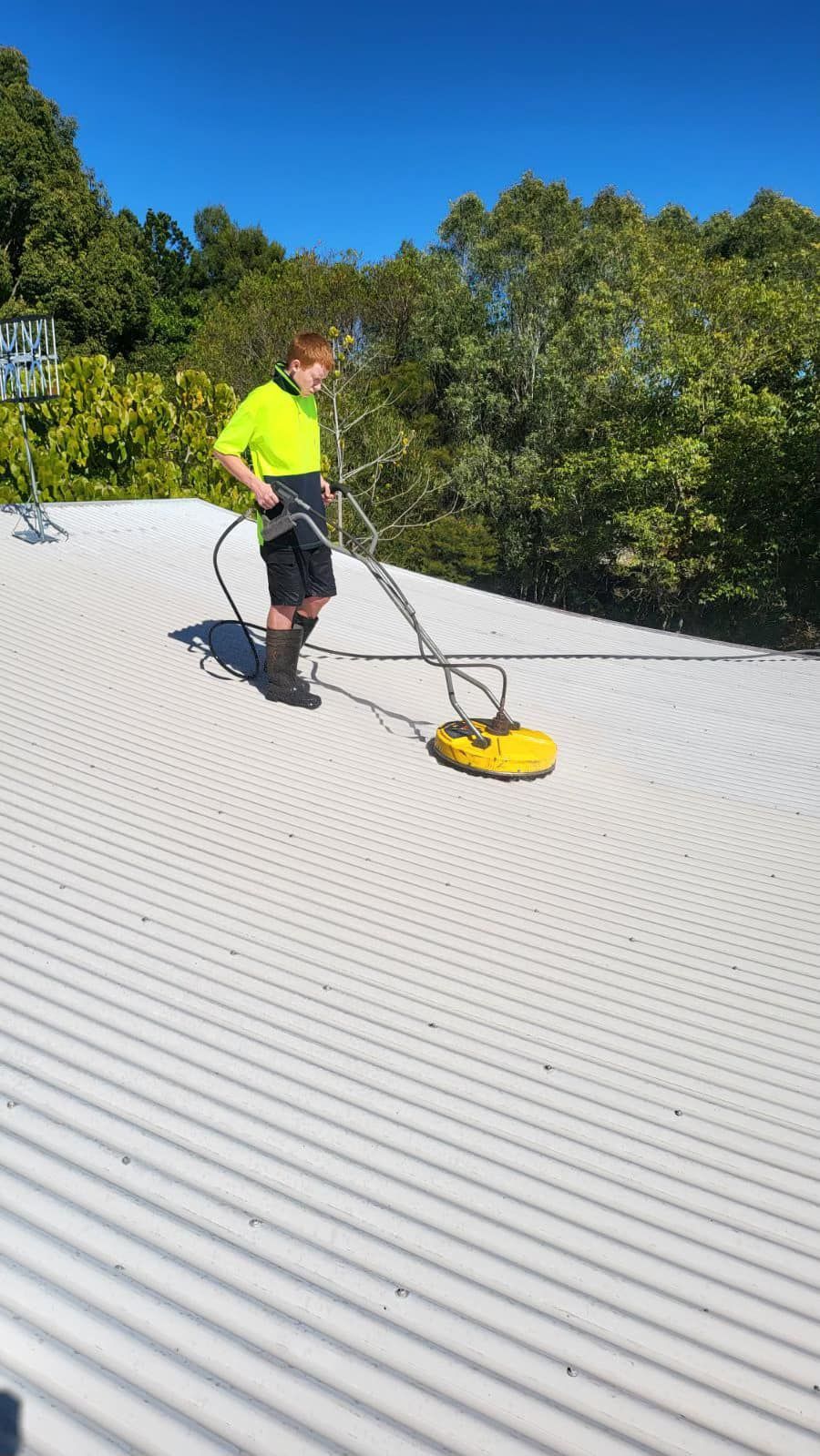 A man is cleaning the roof of a building with a machine. — Roofing Gold Coast in Tallebudgera, QLD