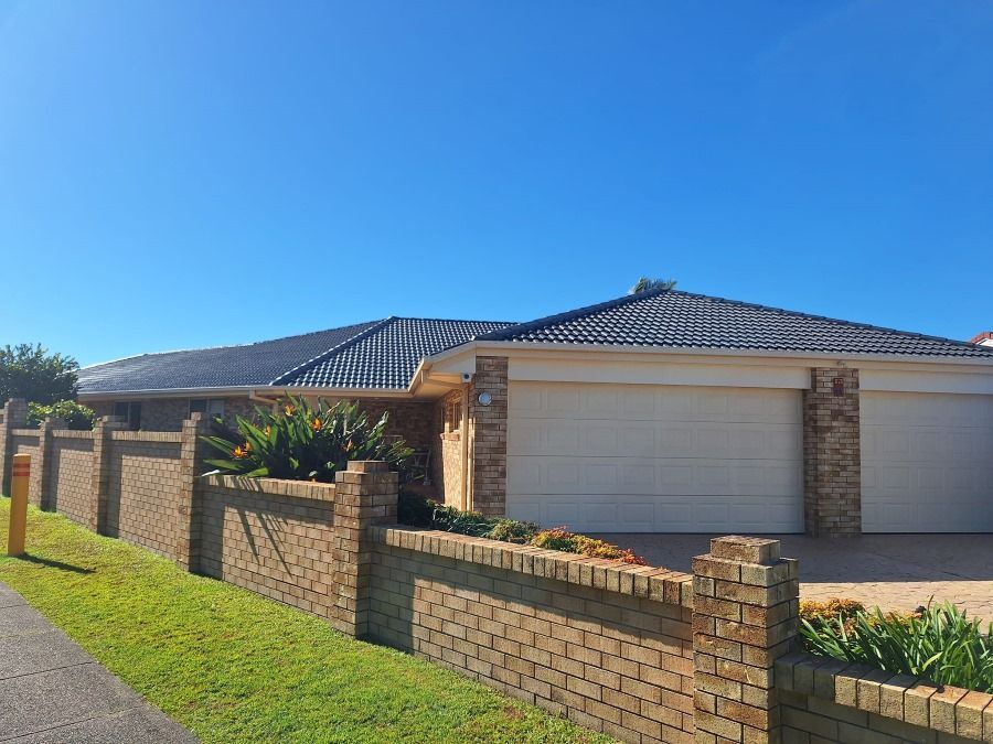 A House With Two Garage Doors and a Brick Fence in Front of It — Roofing Gold Coast in Tallebudgera, QLD