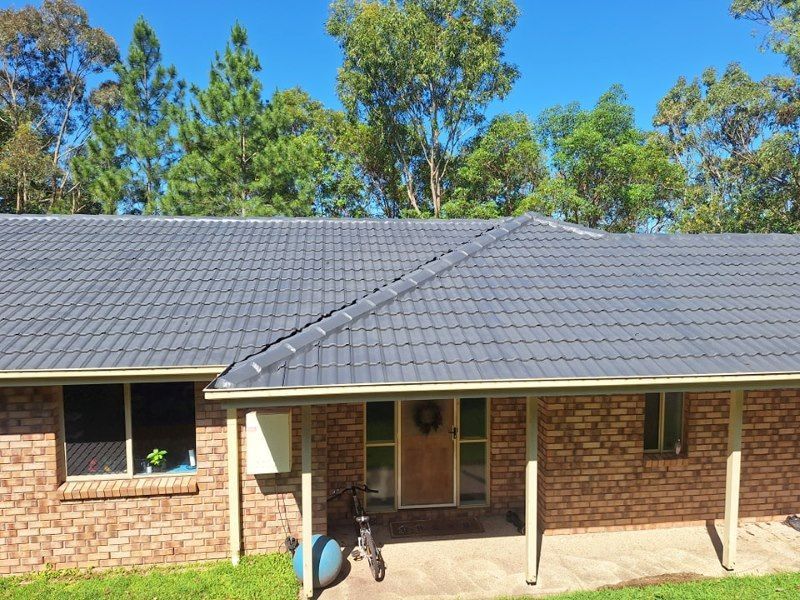 A Brick House With a Black Roof and a Porch — Roofing Gold Coast in Tallebudgera, QLD
