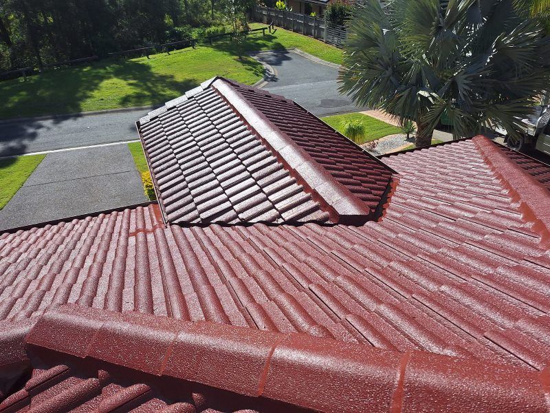 An Aerial View of a Red Tiled Roof With a Driveway in the Background — Roofing Gold Coast in Tallebudgera, QLD
